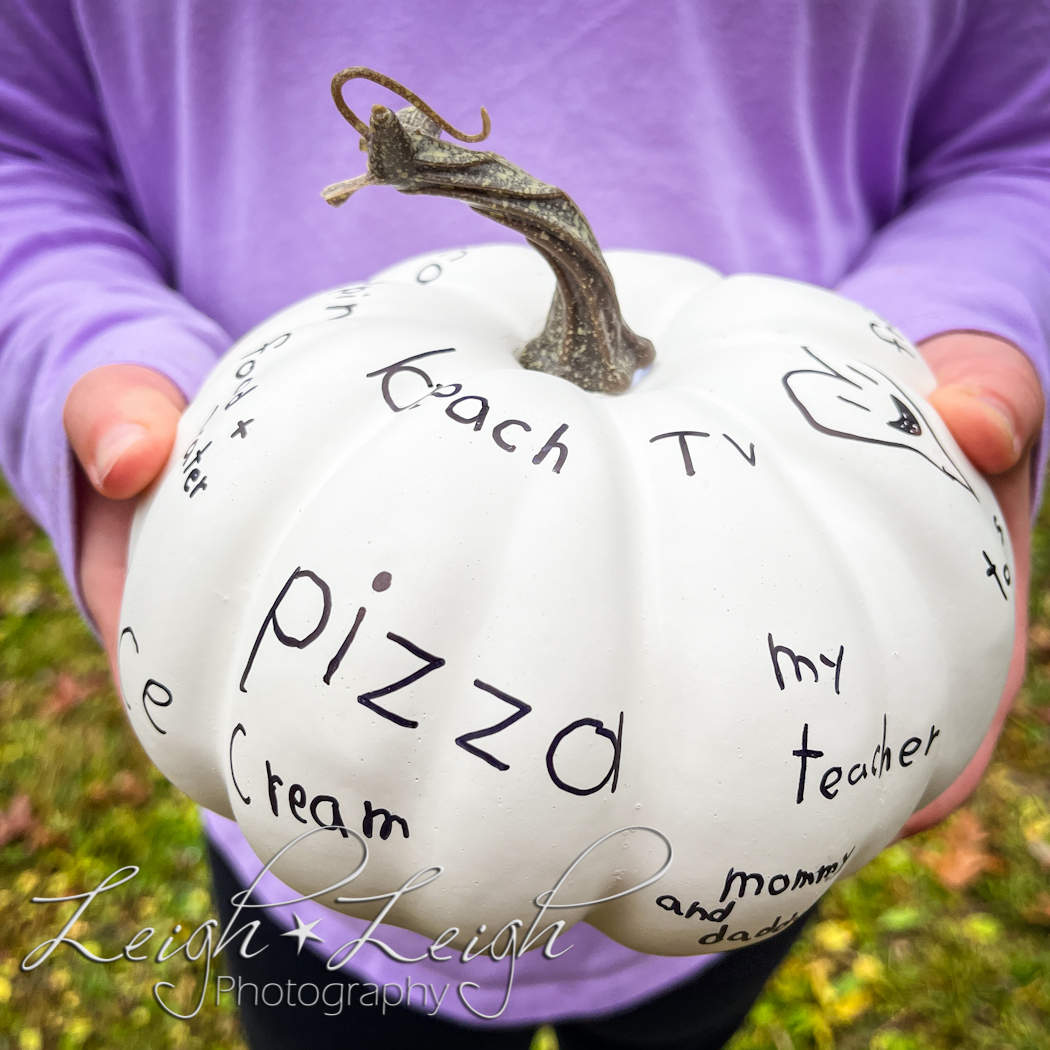 girl holding fake white pumpkin with writing all over it