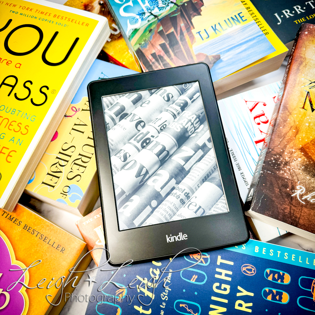 Kindle sitting on a pile of paperback books