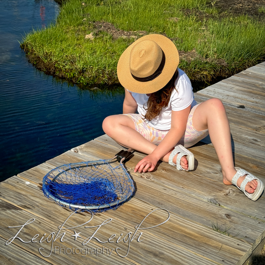 little girl in hat crabbing with net