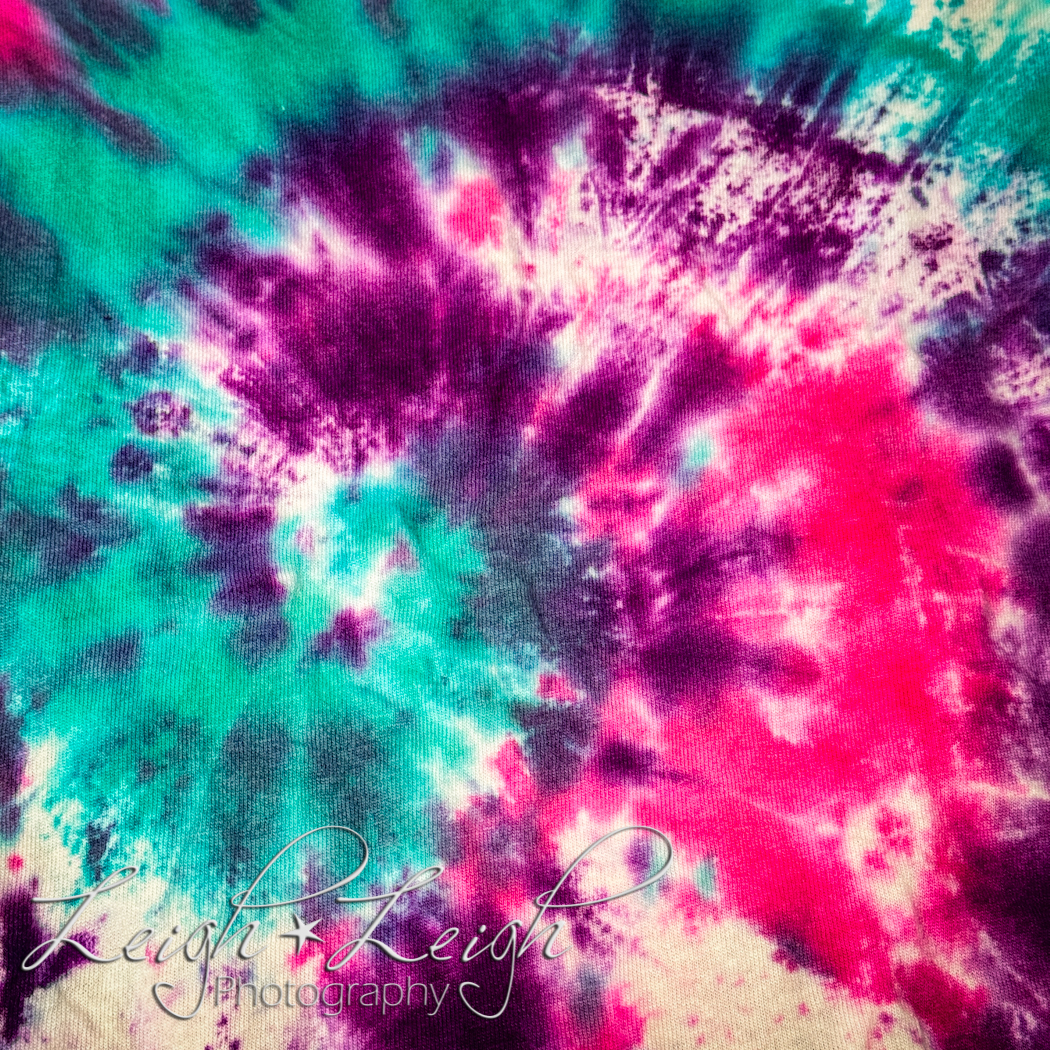 Close up of a tie-dye shirt pattern in pink, purple and teal