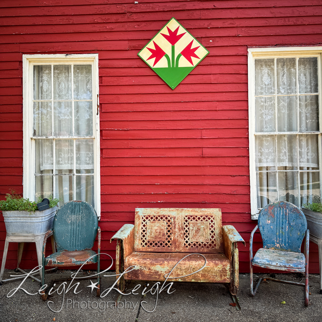 side of red building with antique chairs and flower bins, New Harmony, IN