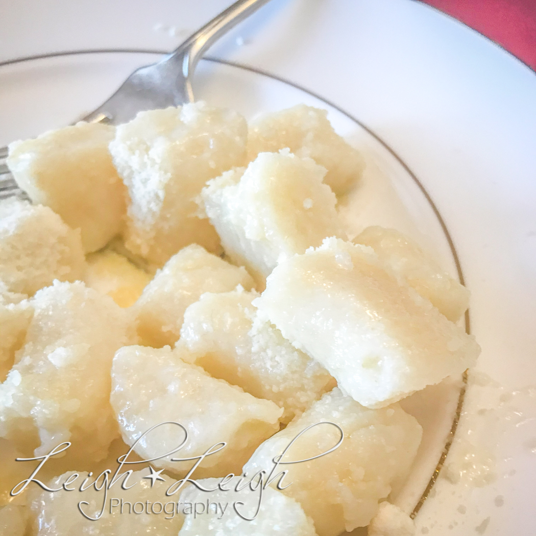 plate of gnocchi topped with butter and parmesan cheese