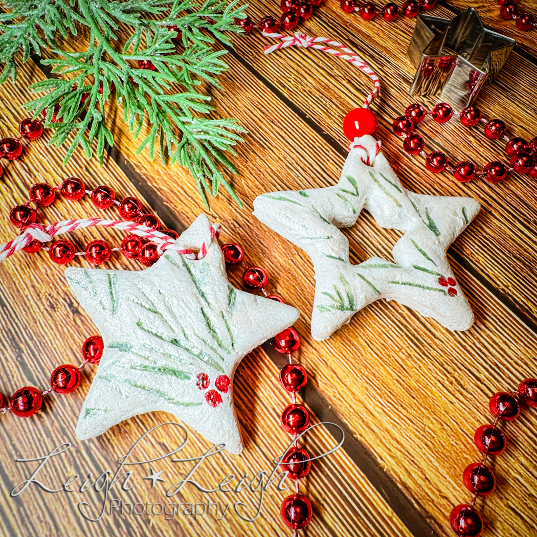 Star ornaments made from dough surrounded by red beads and an evergreen branch