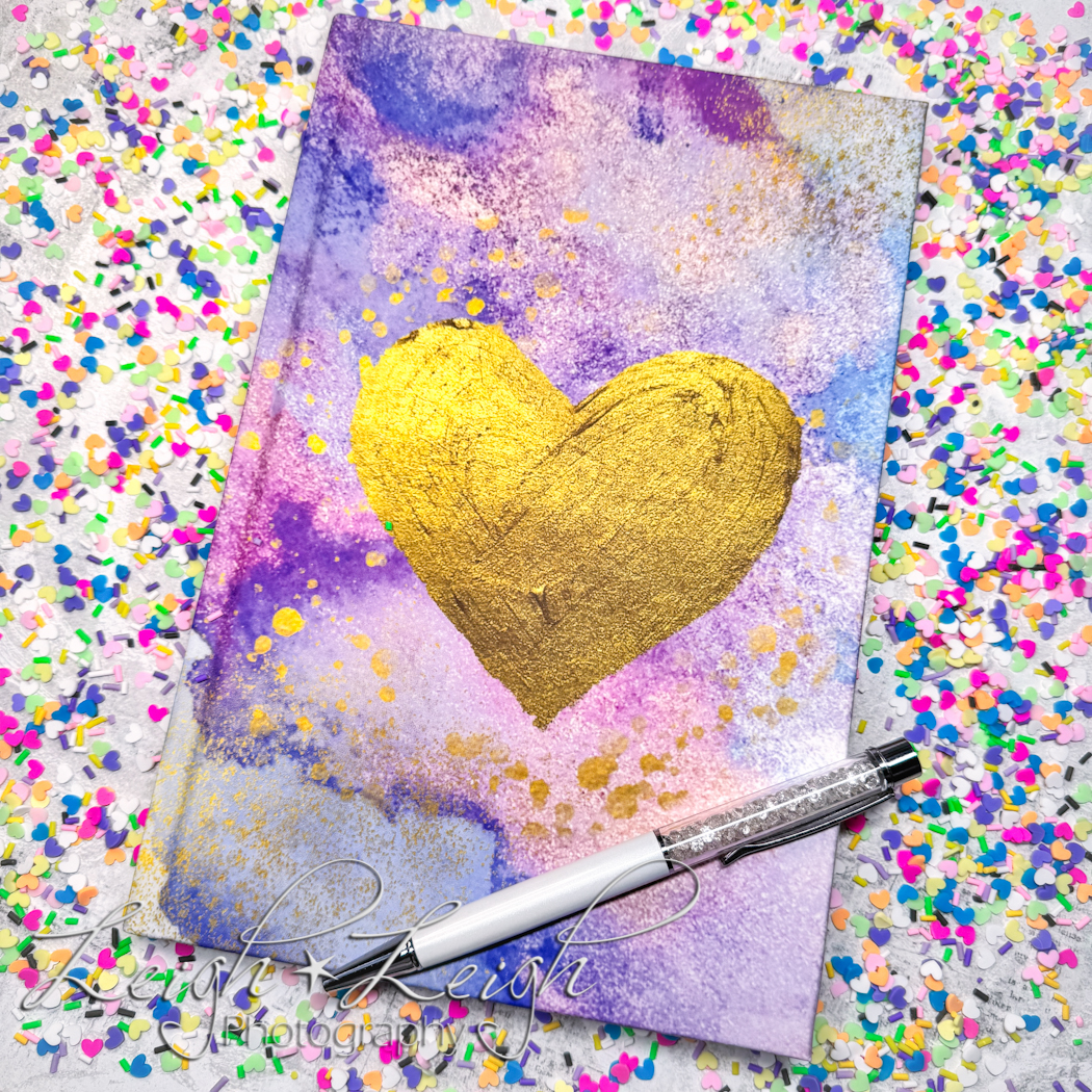 Journal with watercolor design and gold heart surrounded by heart confetti 