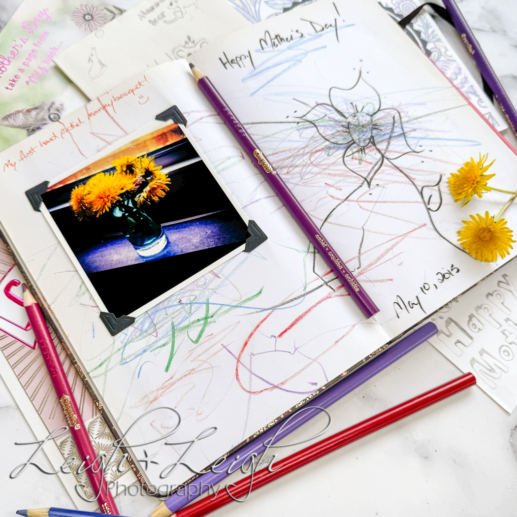Open journal with a picture of dandelions stuck to the page along with colorful scribbles