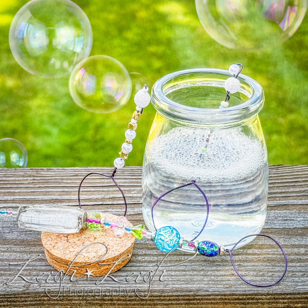 jar of bubble solution with fancy bubble wands and bubbles floating in the air